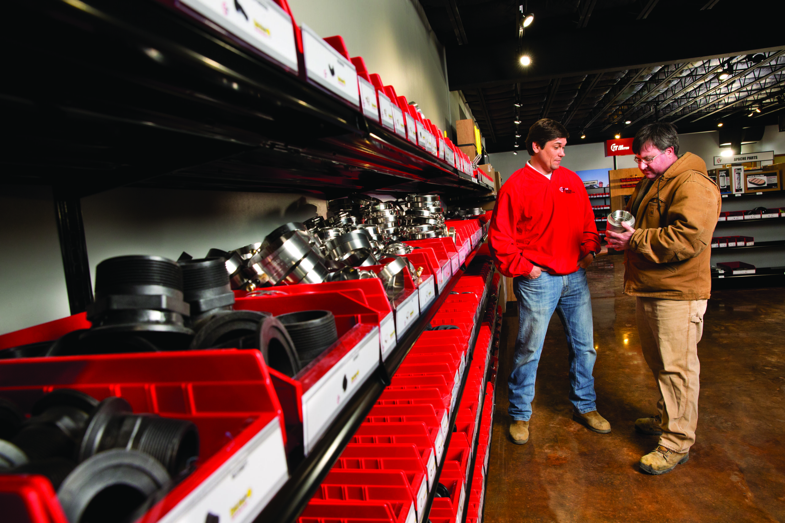 employee and customer looking at and talking about parts on the shelf.